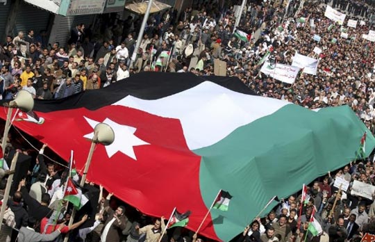 //Jordanian supporters of the Islamic Action Front, carry a giant national  flag as they march during a protest in Amman 25/02/2011.