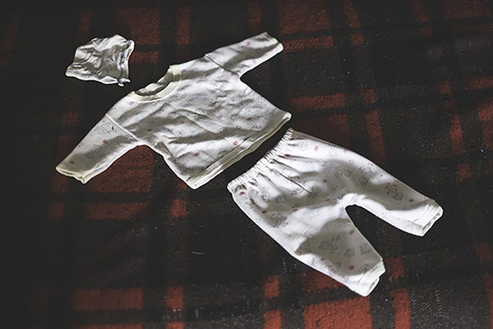 //An outfit belonging to a stillborn baby; the only trace the mother has of her tragic birth at a checkpoint.