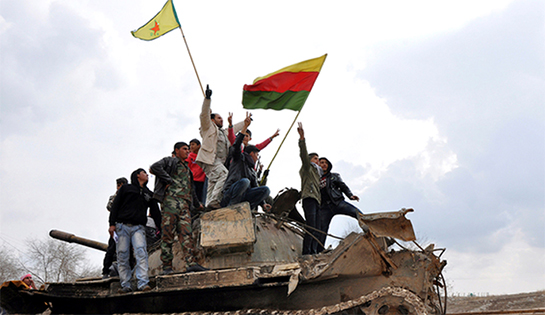 //Civilians and members of the Kurdish People's Protection Units (YPG) gesture and raise flags atop a tank that belonged to fighters from the Islamic State of Iraq in al-Manajeer village of Ras al-Ain countryside, Jan. 28, 2014.  (photo by REUTERS/Rodi Said)