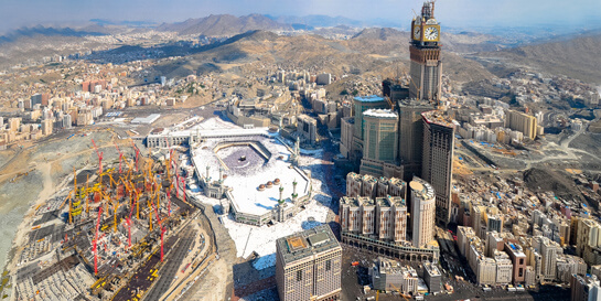 //16 Juillet 2015, au petit matin. Les tours Abraj al-Bait, (la Tour de l’Horloge et l’Hôtel Royal), écrasent de leur masse la mosquée de La Mecque qui peut désormais accueillir 1,85 millions de pèlerins. AFP