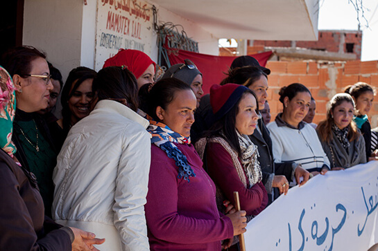 //Les ouvrières à l’entrée de l’usine Mamotex, devant les locaux fermés, tenant une banderole pour revendiquer leur droit au travail, sous le drapeau de l’UGTT, la puissante centrale syndicale. Crédit image: Monia Ben Hamadi 