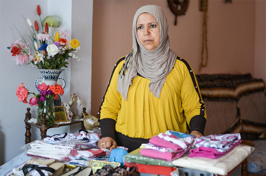 //Wassila se tient derrière le comptoir de son dépôt-vente improvisé dans son garage.