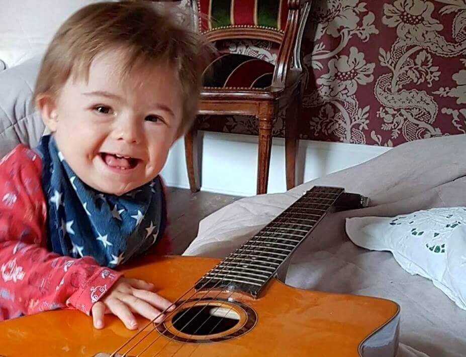 petit enfant avec trisomie 21 joue avec une guitare | Trisomie 21 Nouvelle Aquitaine